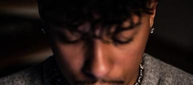 Influencer und Ex-Fußballer Kevin Plath trägt einen grauen Pullover und schaut nach unten in sein Handy.