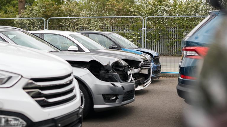 Beschädigte PKW stehen auf einem Parkplaz.