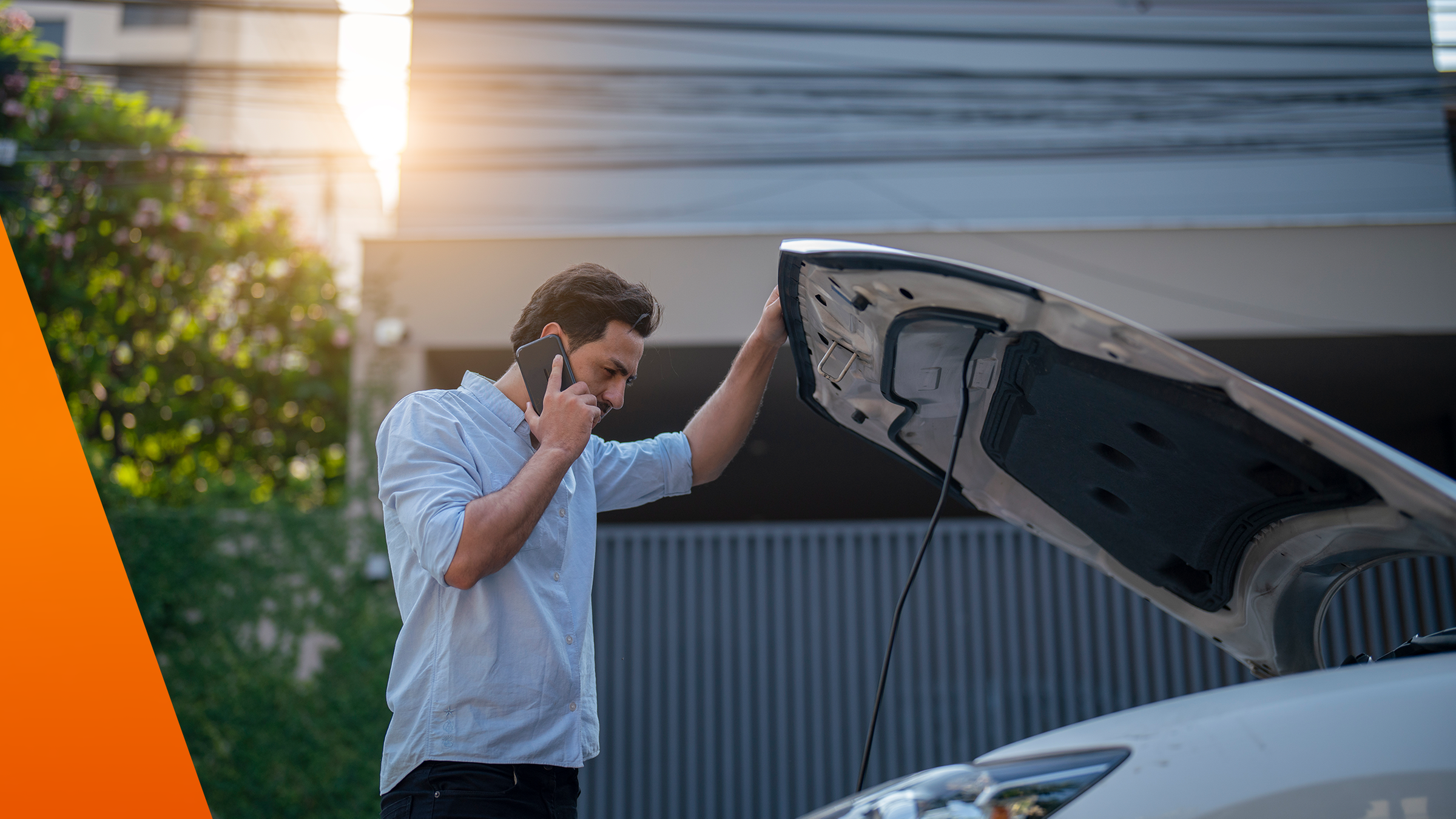 Mann hat die Motorhaube seines Autos geöffnet und telefoniert