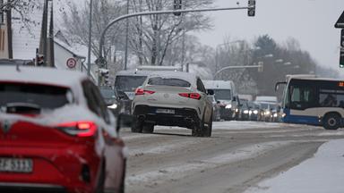 Schnee liegt auf den Zufahrtstraßen in die Stadt, die Autos stauen sich.