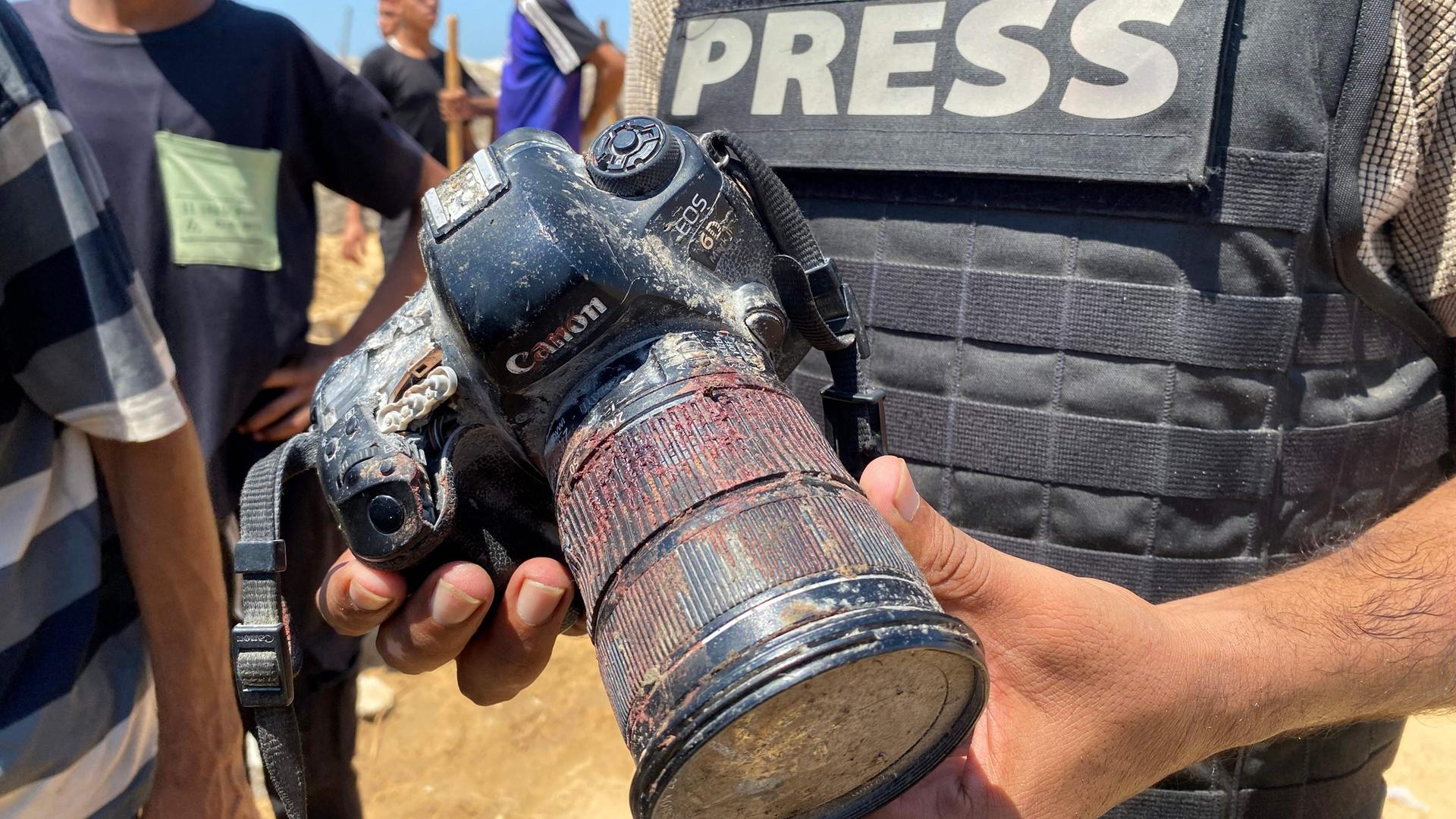 Ein Journalist hält eine blutverschmierte Kamera, die dem palästinensischen Fotojournalisten Hussam al-Masri gehörte, einem Reuters-Mitarbeiter, der bei einem israelischen Angriff auf das Nasser-Krankenhaus in Khan Yunis im südlichen Gazastreifen getötet wurde.