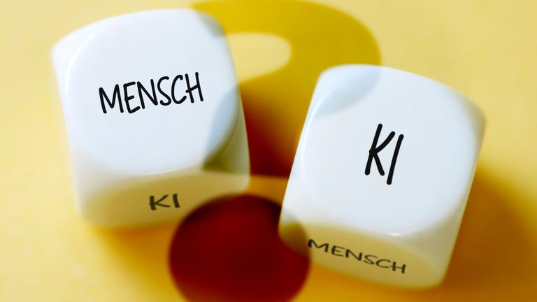 Es sind zwei Würfel zu sehen mit der jeweiligen Aufschrift "KI" und "Mensch"