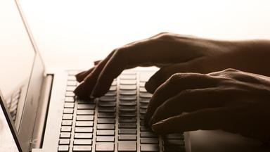 Die Hände einer Person, die auf die Tastatur eines Laptops tippt.