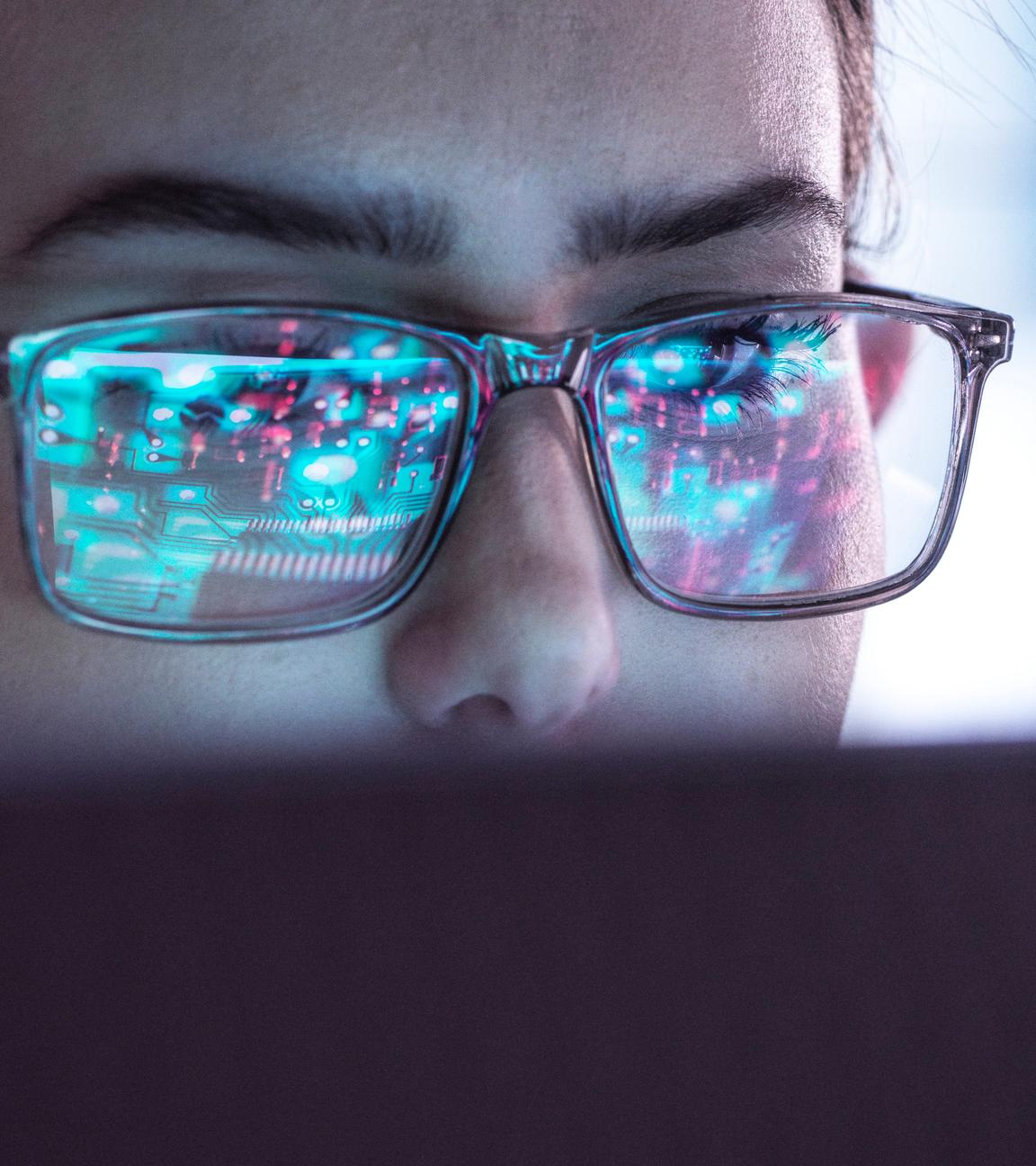 Eine Frau mit Brille blickt auf einen Computerbildschirm.