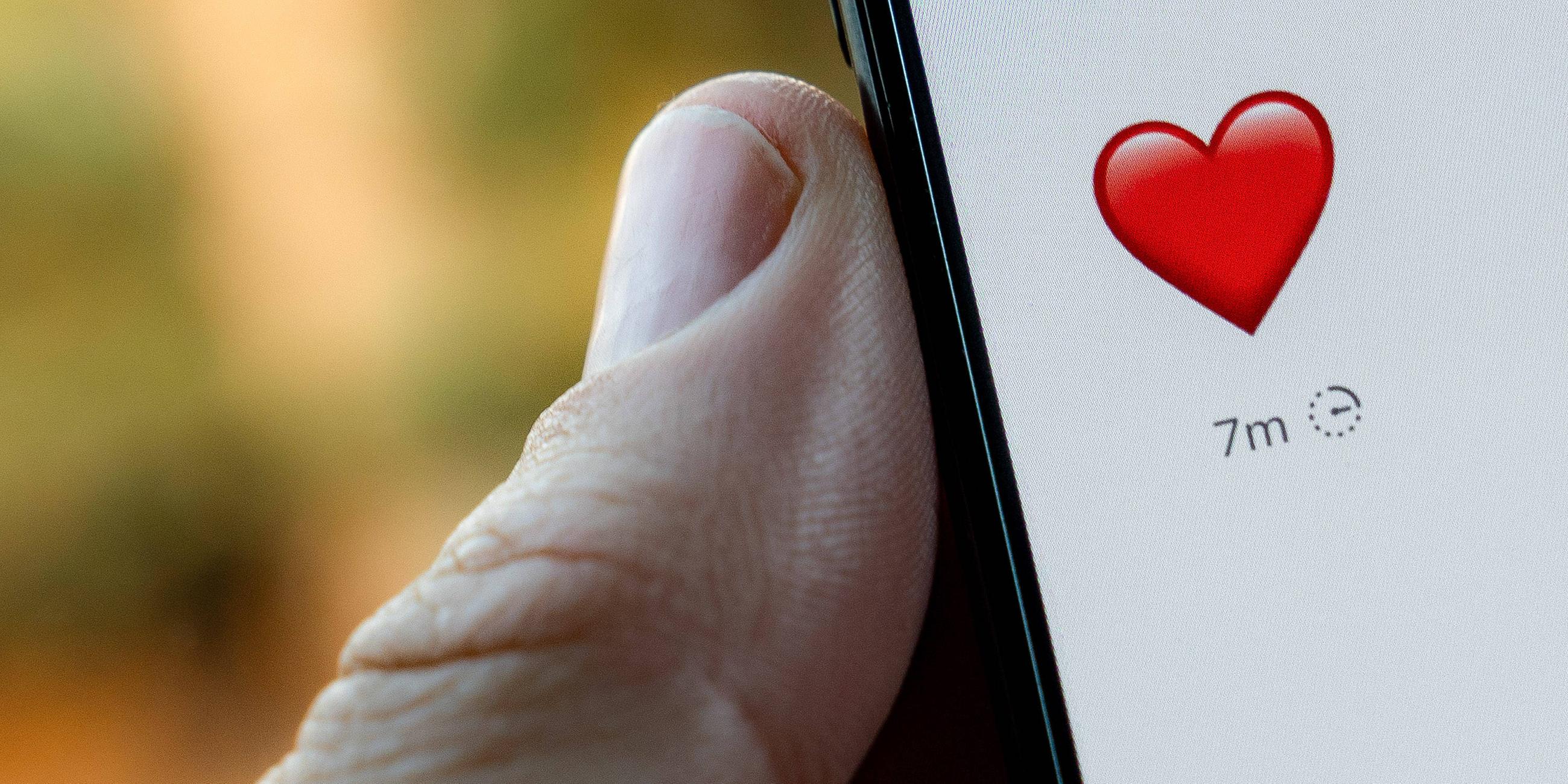 Nachricht mit einem Herz auf einem Smartphone, das von einem Mann gehalten wird