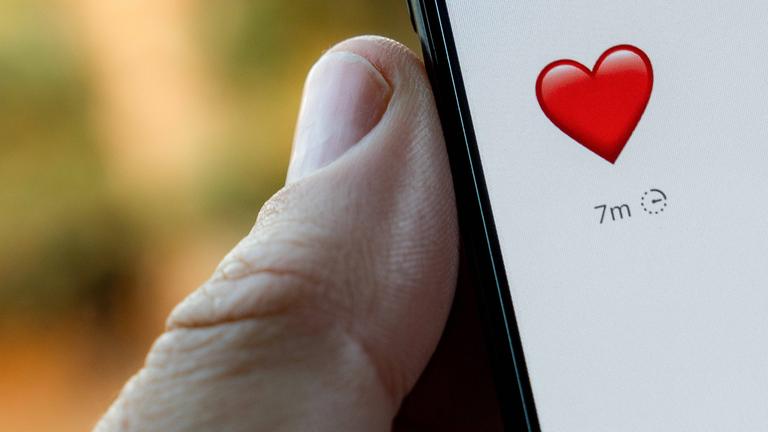 Nachricht mit einem Herz auf einem Smartphone, das von einem Mann gehalten wird