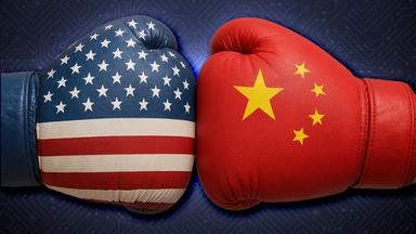 Zwei große Boxhandschuhe, die in der Mitte gegeneinander stoßen. Der linke Handschuh mit der Fahne der USA, der rechte Handschuh mit der Fahne von China
