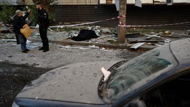 Ein Polizist spricht mit einem Anwohner neben den Leichen zweier Menschen, die bei einem nächtlichen russischen Angriff ums Leben gekommen sind. 