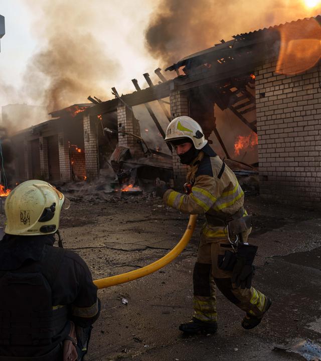 Rettungskräfte löschen in Kiew ein Feuer in einer Autowerkstatt, die durch einen russischen Angriff beschädigt wurde. 