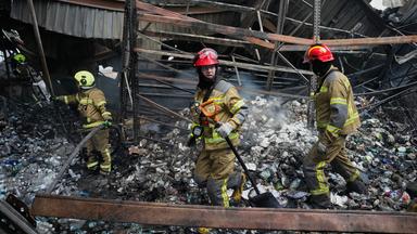 Ukrainische Feuerwehrmänner stehen in einem zerstörten Haus