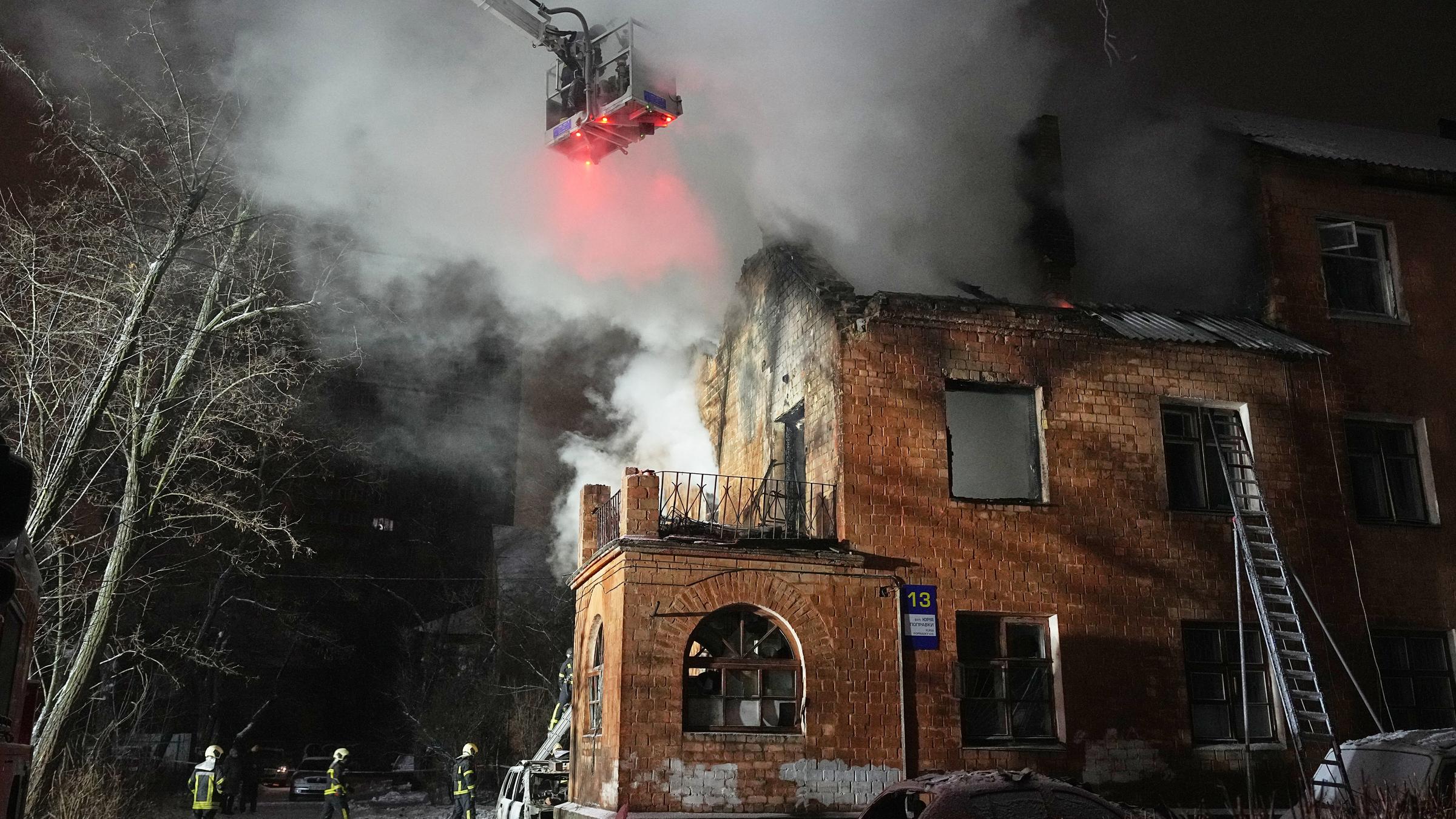 Rettungskräfte löschen ein Feuer in einem Wohnhaus, das durch einen russischen Angriff beschädigt wurde.