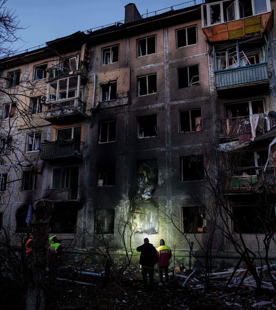 14.11.2025, Ukraine, Kiew: Arbeitskräfte der örtlichen Behörden betrachten ein Wohnhaus, das nach einem russischen Angriff auf Kiew beschädigt wurde.