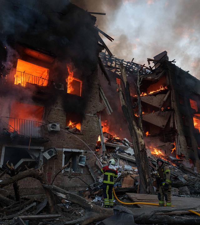 Rettungskräfte löschen ein Feuer in einem Wohnhaus, das nach einem russischen Angriff in Kiew zerstört wurde.