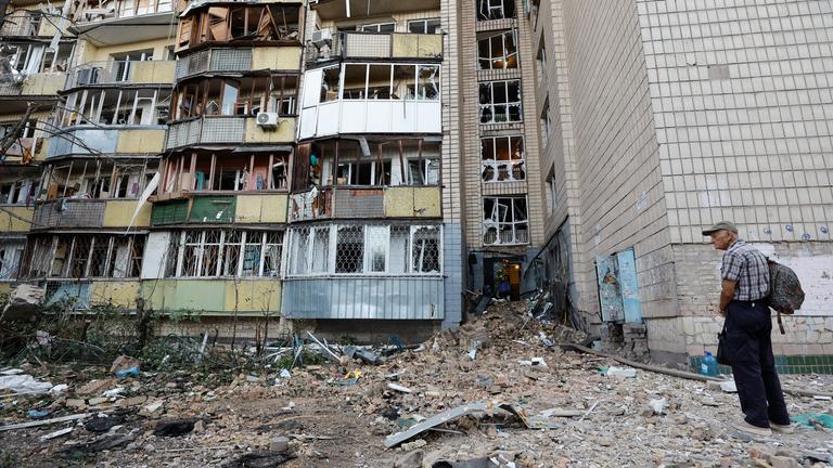 Ein Mann steht vor einem zerstörten Wohnhaus nach den russischen Angriffen auf Kiew am 20. August 2026.