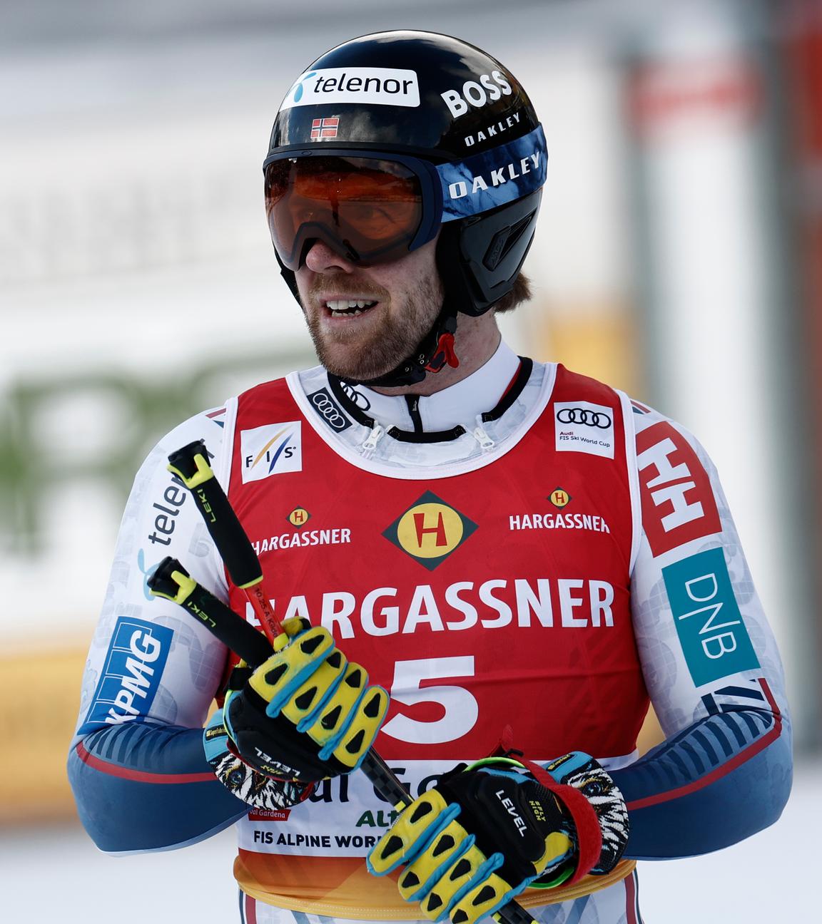 Aleksander Aamodt Kilde mit Skihelm und Stöcken in der Hand blickt nach rechts.