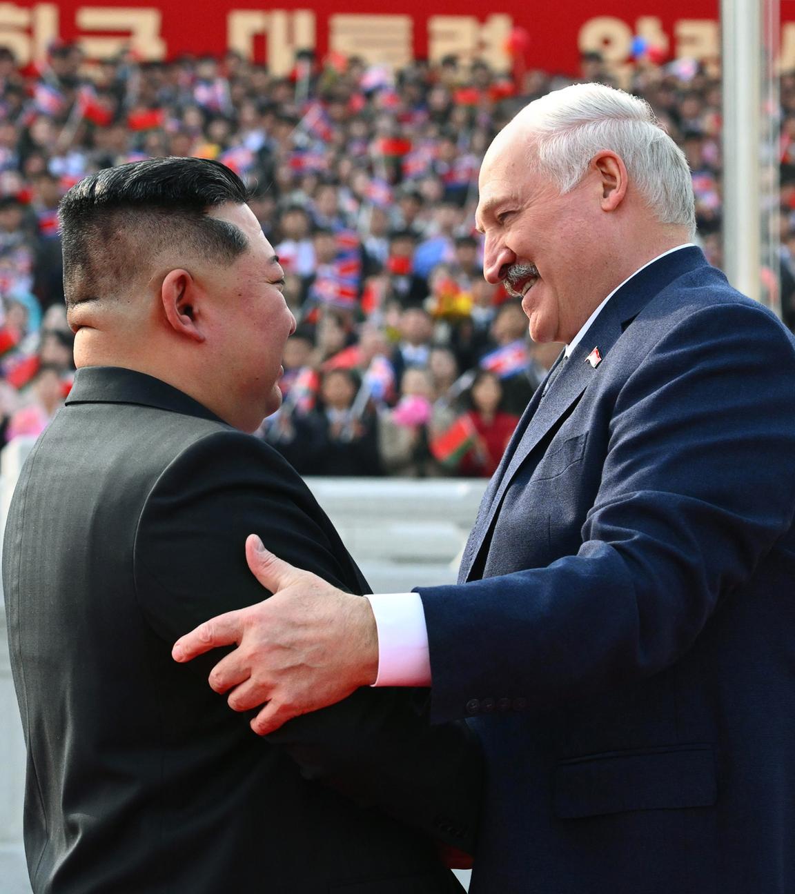 Kim Jong-un und Alexander Lukaschenko in freundschaftlicher Begrüßung vor einer Tribüne mit nordkoreanischem Publikum