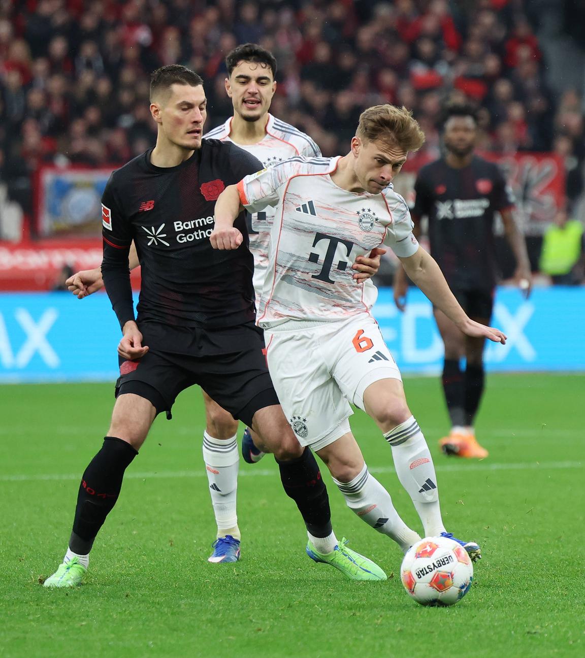 Leverkusens Mittelstürmer Patrick Schick packt Bayerns Mittelfeldspieler Joshua Kimmich von hinten an