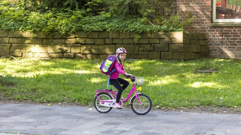Kind fährt auf dem Gehweg Fahrrad