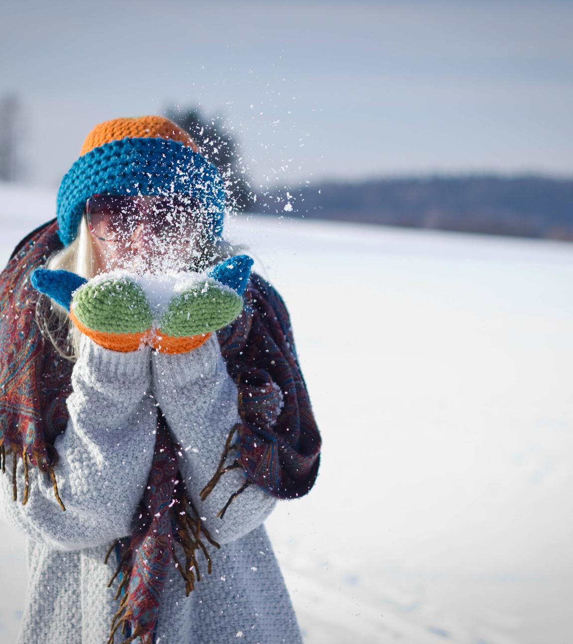 Jugendliche pustet Schnee aus den Händen
