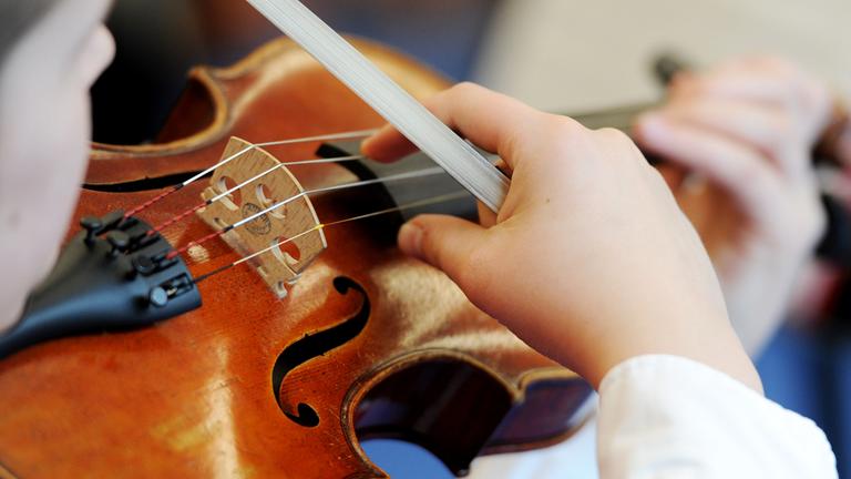 Auf dem Bild sieht man ein Mädchen, was Geige übt.