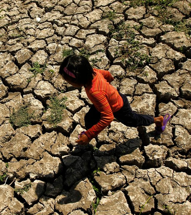 Ein Kind läuft in der Provinz Cavite auf den Philippinen in einem ausgetrockneten Bewässerungskanal, der durch das Wetterphänomen El Niño ausgetrocknet war. 