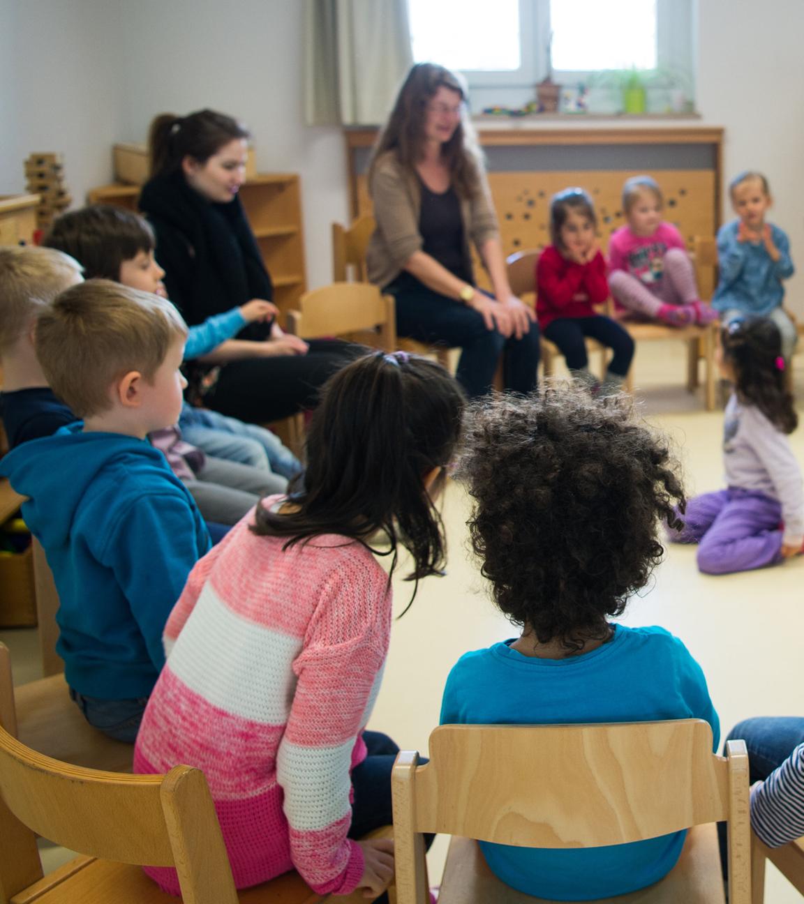 Kinder und Erzieherinnen im Stuhlkreis in einer Kita