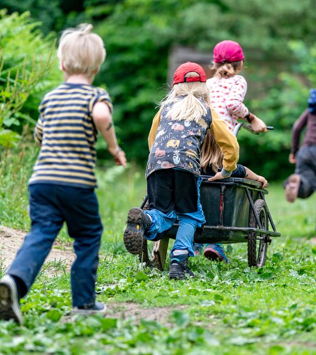 Schleswig-Holstein, Preetz: Kinder der Kita Wühlmäuse spielen im Wald mit einem Anhänger.