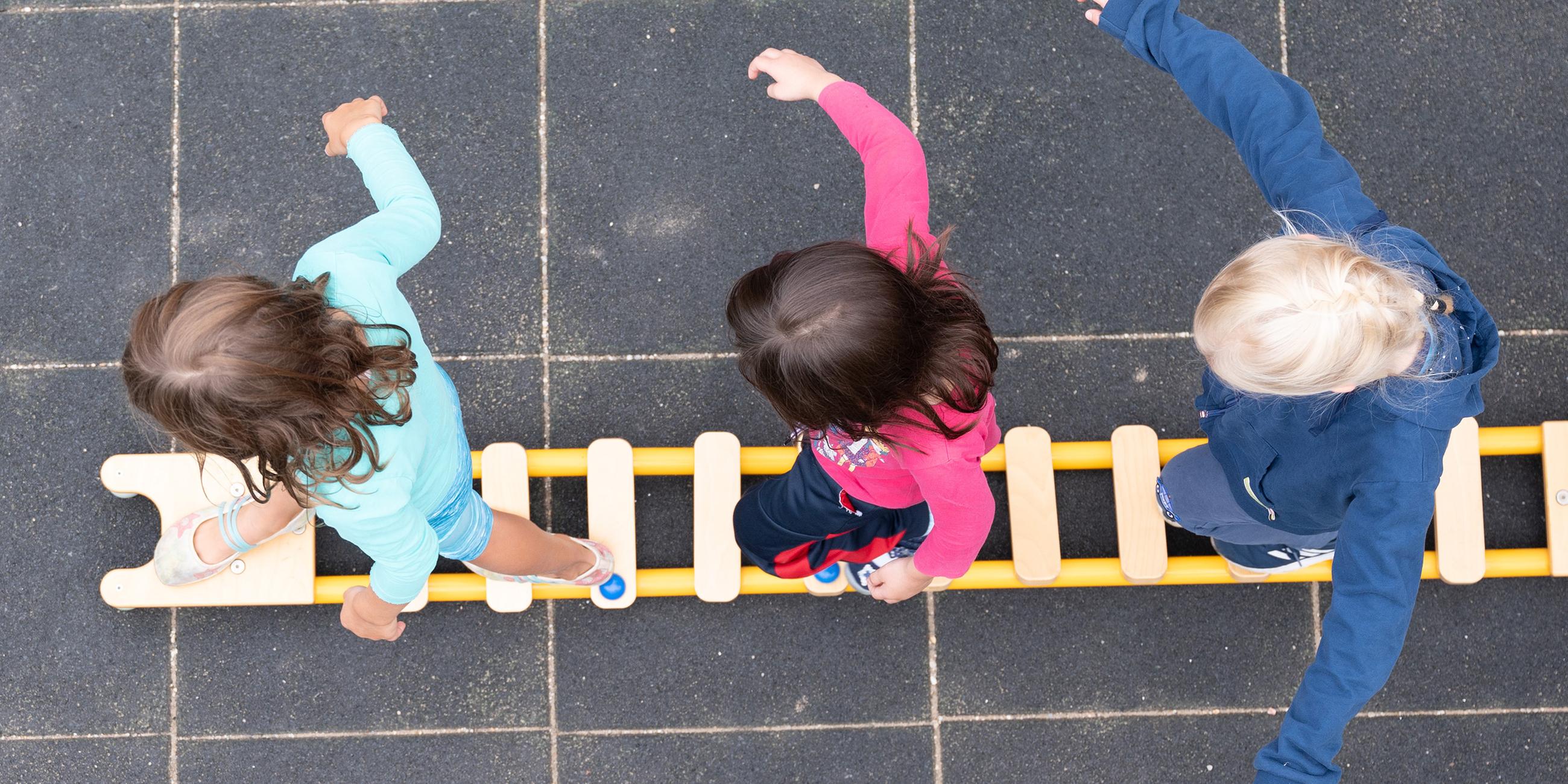 Kinder balancieren auf dem Spielplatz einer Kindertagesstätte