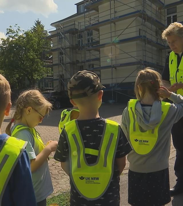 Vorschulkinder in gelben Westen üben den Schulweg