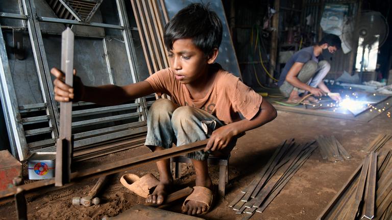 Ein Junge arbeitet in einer Werkstatt in Bangladesch.