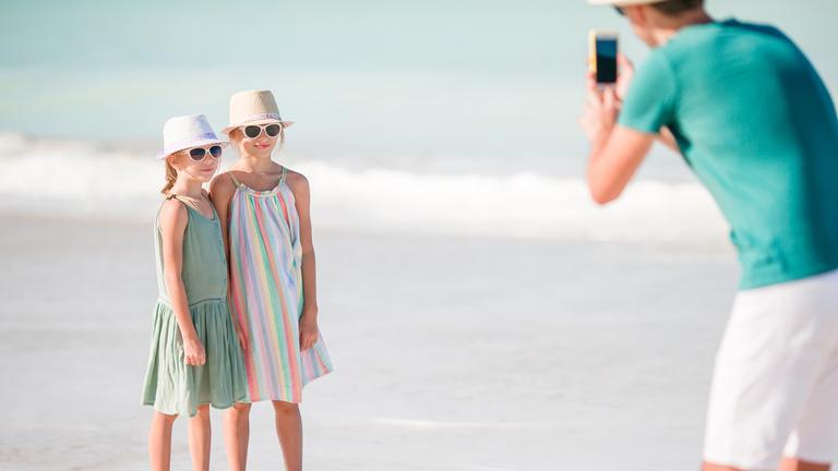 Mann fotografiert seine Kinder am Strand.