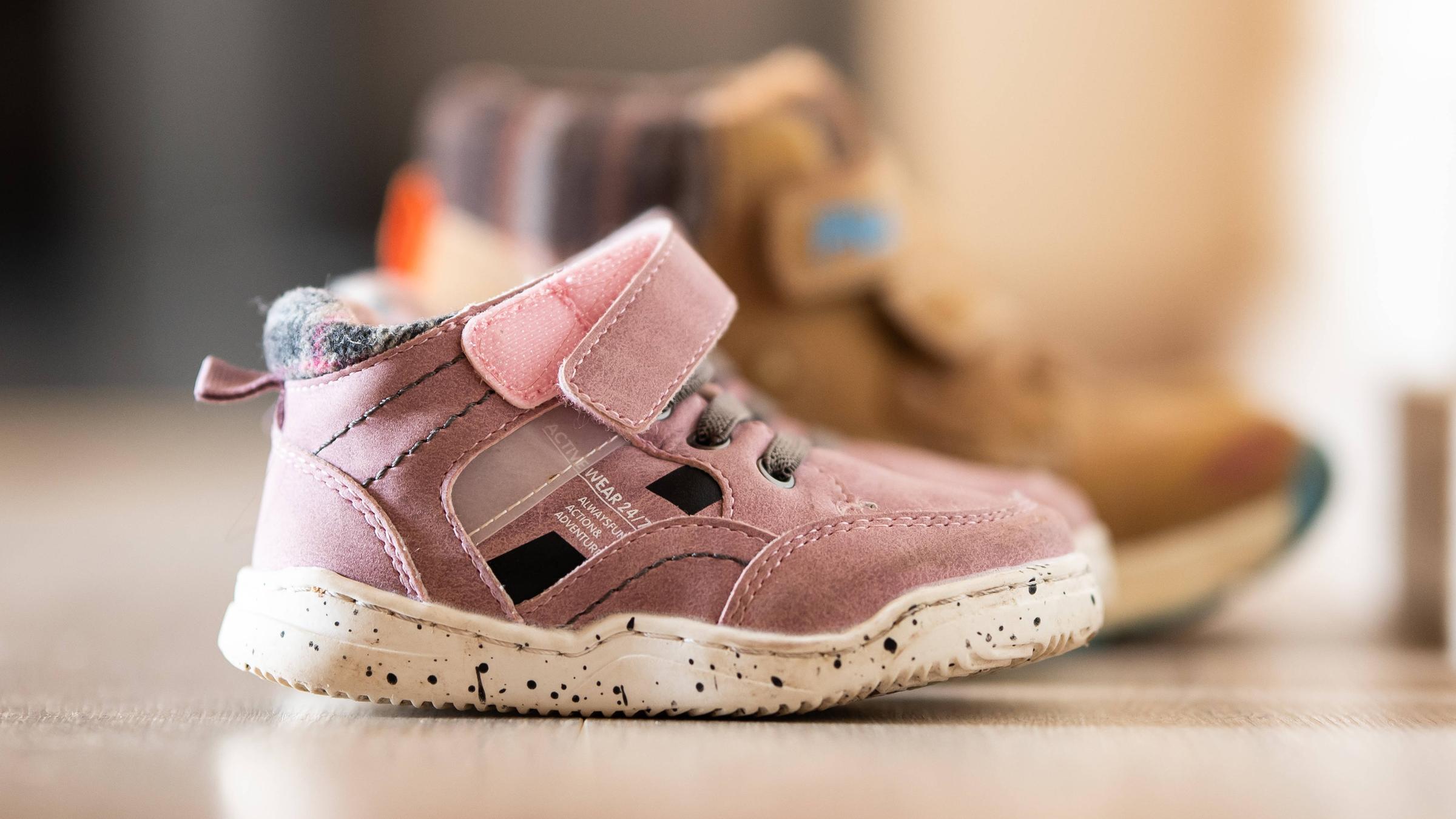 Auf dem Boden stehen zwei Paar Kinderschuhe.