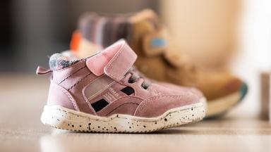 Auf dem Boden stehen zwei Paar Kinderschuhe.