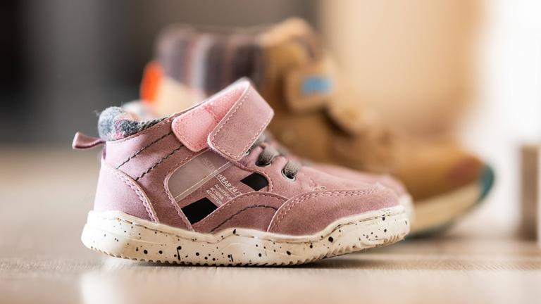 Auf dem Boden stehen zwei Paar Kinderschuhe.