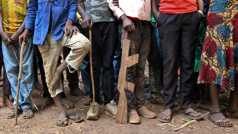 Ehemalige Kindersoldaten warten, um von UNICEF registriert zu werden. Sie haben Waffen aus Holz.