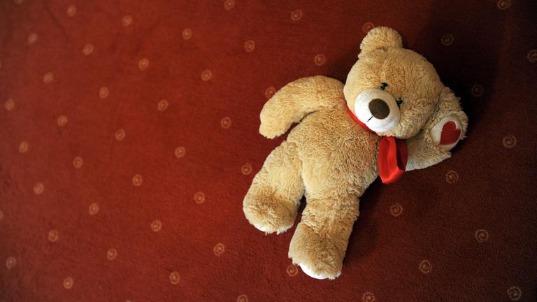 Ein Teddybär liegt auf dem Boden.