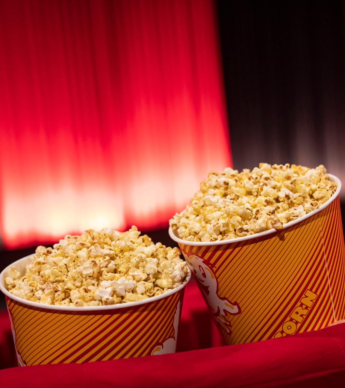 Zwei Tüten voller Popcorn in einem leeren Kinosaal
