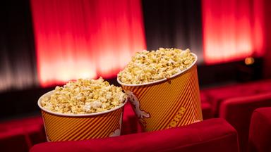 Zwei Tüten voller Popcorn in einem leeren Kinosaal