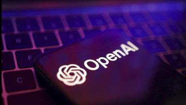 Das Logo von OpenAI - dahinter sind die Umrisse einer Computer-Tastatur.
