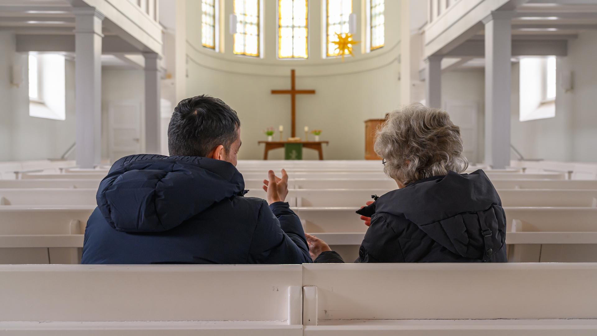 Brandenburg, Seelow: In der Kirche von Seelow unterhält sich eine Frau der Kirchengemeinde mit einem Geflüchteten aus Afghanistan.