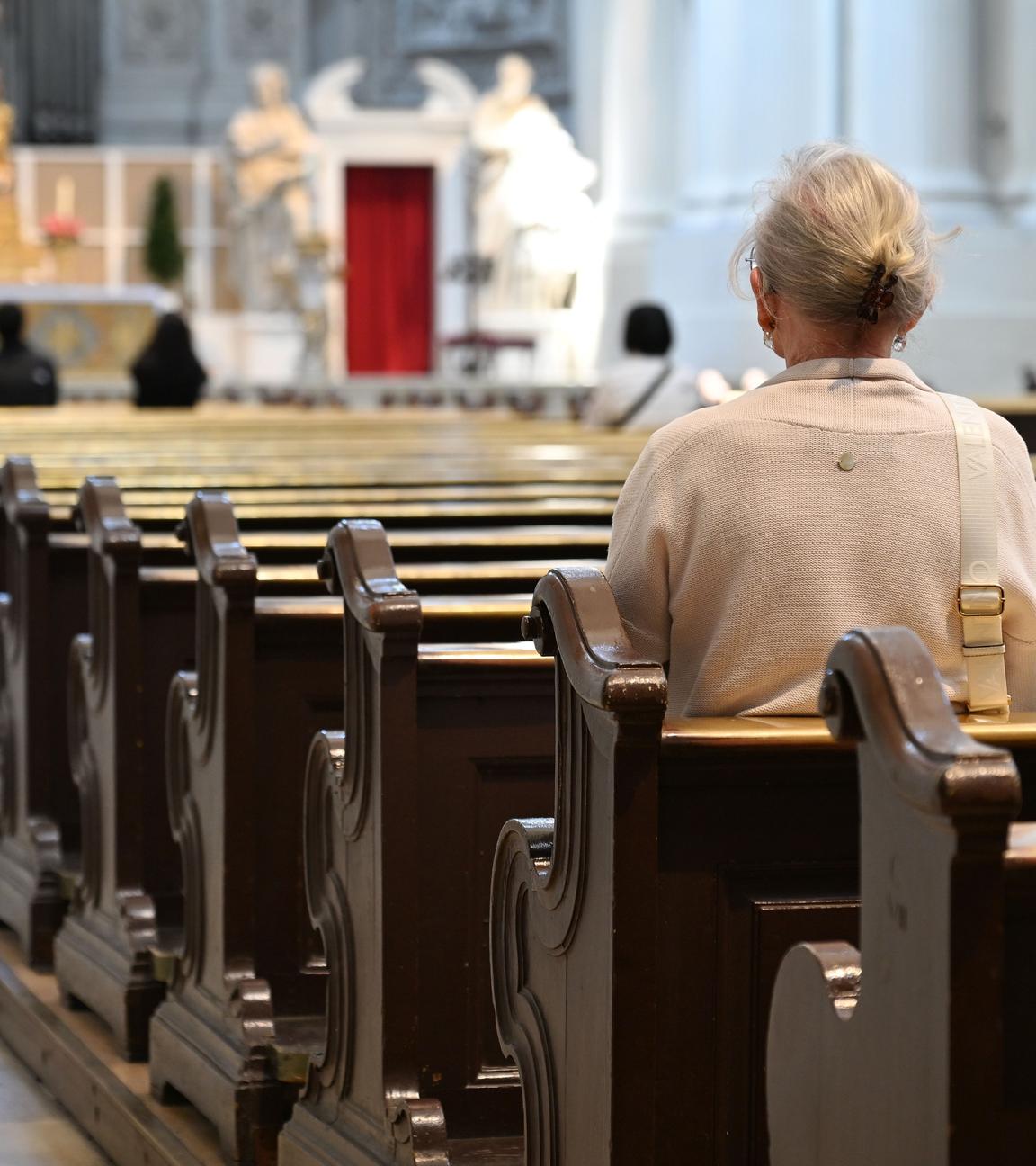 Eine Frau sitzt allein in einer Kirche.  