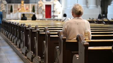 Eine Frau sitzt allein in einer Kirche.  