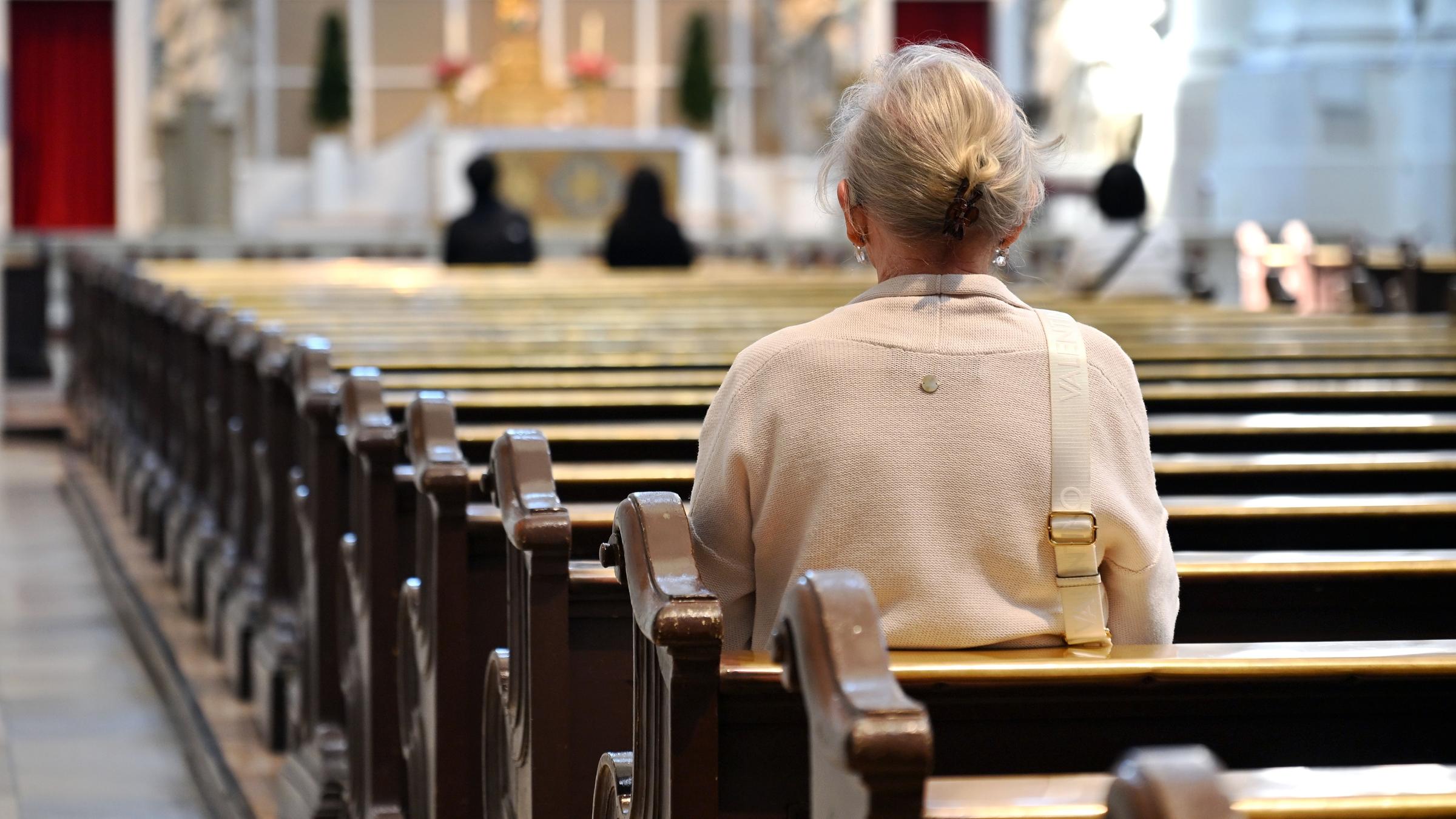 In einer fast leeren Kirche sitzt nur eine ältere Person auf der Kirchbank.