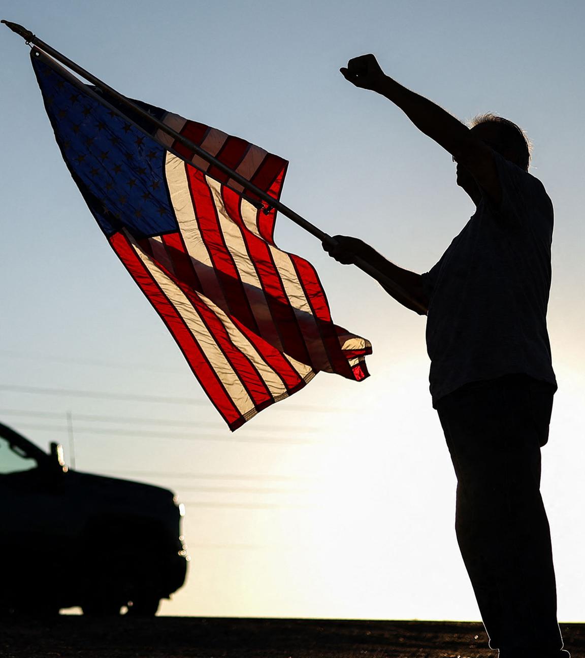 Ein Mann mit einer US-Flagge hebt die Faust, während am 13. September 2025 in Surprise, Arizona, eine Kundgebung zum Gedenken an den rechten Aktivisten Charlie Kirk vorbeizieht.