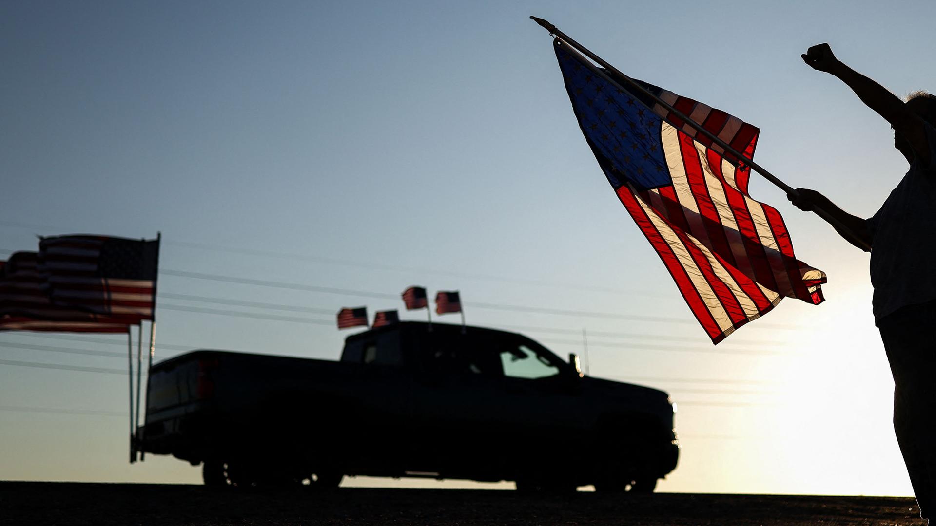 Ein Mann mit einer US-Flagge hebt die Faust, während am 13. September 2025 in Surprise, Arizona, eine Kundgebung zum Gedenken an den rechten Aktivisten Charlie Kirk vorbeizieht.