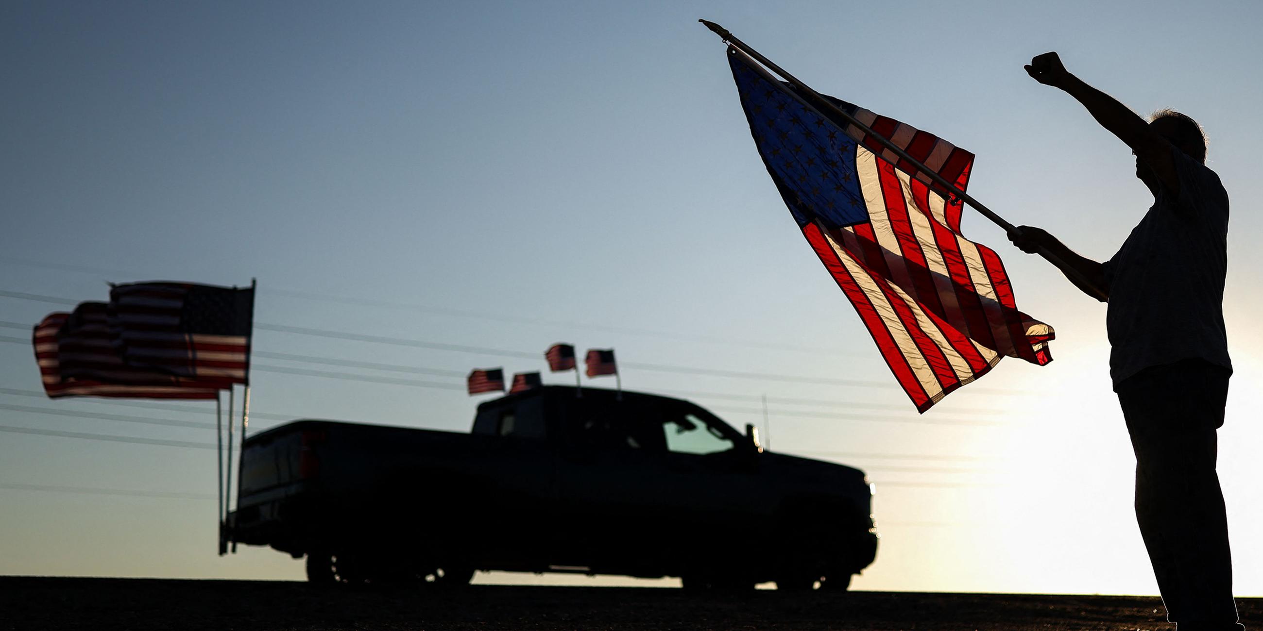 Ein Mann mit einer US-Flagge hebt die Faust, während am 13. September 2025 in Surprise, Arizona, eine Kundgebung zum Gedenken an den rechten Aktivisten Charlie Kirk vorbeizieht.