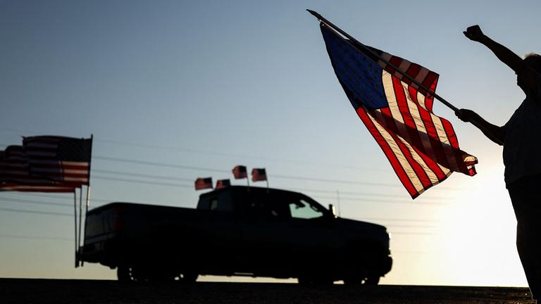 Ein Mann mit einer US-Flagge hebt die Faust, während am 13. September 2025 in Surprise, Arizona, eine Kundgebung zum Gedenken an den rechten Aktivisten Charlie Kirk vorbeizieht.