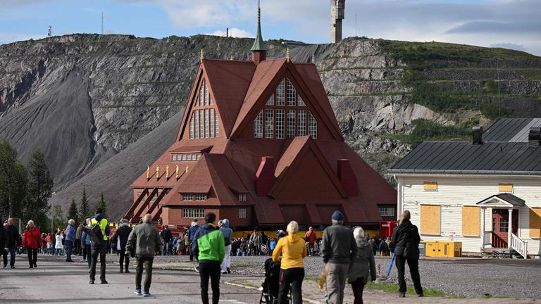 Schweden, Kiruna: Die Kirche aus Holz wird transportiert, während viele Menschen zuschauen.