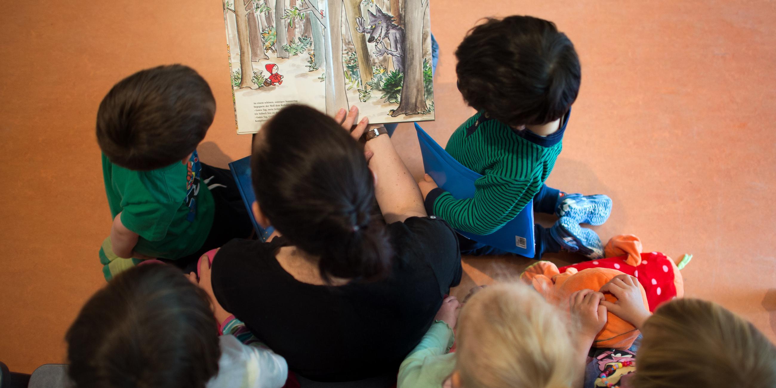 Eine Kindergärtner liest Kindern vor (Archivbild)