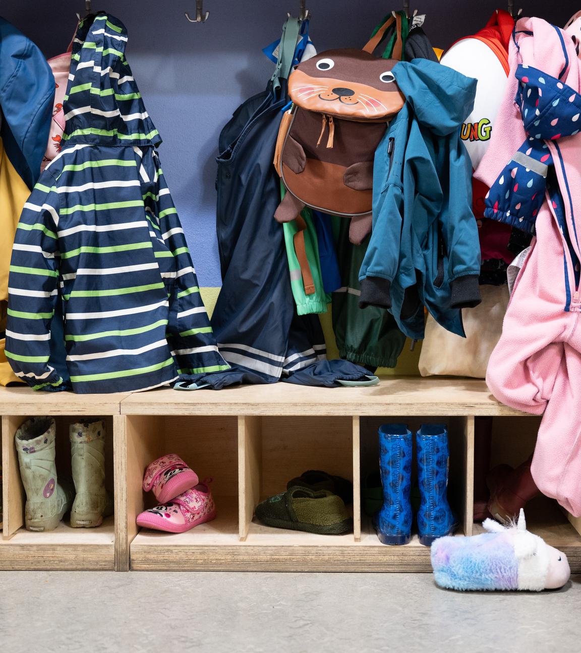 Jacken und Schuhe befinden sich in einer Garderobe in einer Kita in Dresden. 